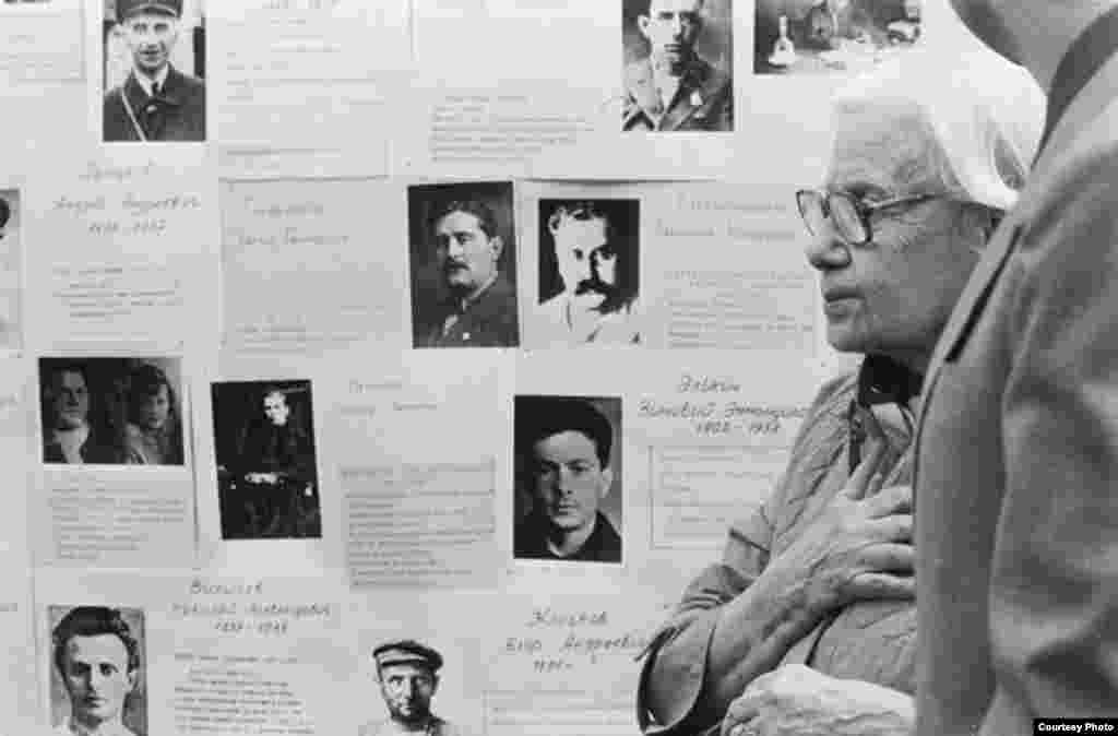 The first historical exhibition devoted to the Stalinist repressions. A woman former prisoner of the GULAG against a background of stands with biographies of victims of Stalinism. Moscow, 1988