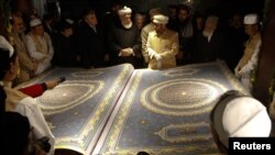 Afghan calligrapher Mohammad Sabir Khedri (center right) presents the biggest Koran in the world to Afghan officials during its inauguration ceremony in the Hakim Nasir Khosrow Balkhi library in Kabul on January 12.