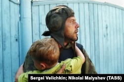 Российский солдат держит на руках ребенка, бывшего в заложниках. Фото ТАСС