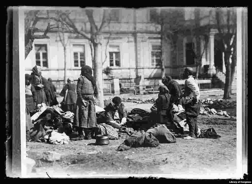 Refugees at an American Red Cross hospital in what is today North Macedonia in July 1919. The barefoot man on the right had just visited the bathhouse in the background. The others are waiting their turn. Bathing was compulsory to prevent the spread of typhus.