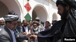 The governor of Afghanistan's southern Helmand Province receives a rifle from a Taliban fighter who said he wanted to return to normal life. Kabul hopes to make such moves more common.