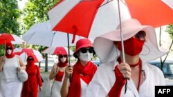 Женщины с бело-красно-белыми зонтиками в Минске, июль 2021 года