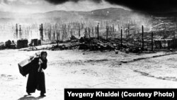 Sovet Murmanskı. 1942-ci ildə hitlerçilər şəhərin bütün şimal-qərb bölümünü yandırıcı bombalarla dağıdıblar. Günboyu 350-dən çox mərmi atılıb. Khaldei xatırlayır ki, qadın onu dağıntıları çəkdiyi üçün söyür və belə deyirmiş:“Siz niyə gedib Berlində bizim pilotların oranı bombalamasını çəkmirsiniz?”. Fotoqraf ona söz verib ki, Almaniyaya gedə bilsə, “məhz bu işi görəcək”.