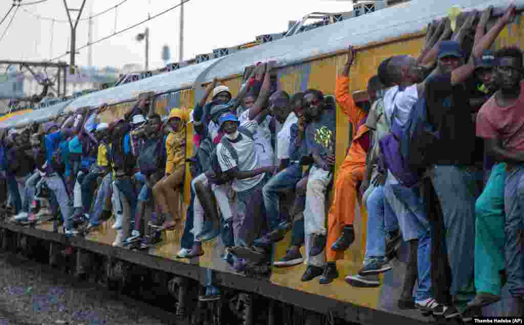 Train commuters hold on to the side of an overcrowded passenger train in Soweto, South Africa. (AP/Themba Hadebe)