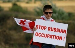 Протестувальник тримає плакат із написом «Зупиніть російську окупацію» під час антиросійського мітингу біля лінії розмежування з окупованим регіоном Південної Осетії в селі Хурвалеті 14 липня 2015 року