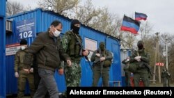Un prizonier de război escortat de militarii autoproclamatei regiuni în timpul schimbului de prizonieri între Ucraina și separatiștii pro-ruși, în apropiere de punctul de trecere Mayorsk în regiunea Donețk , 16 aprilie 2020