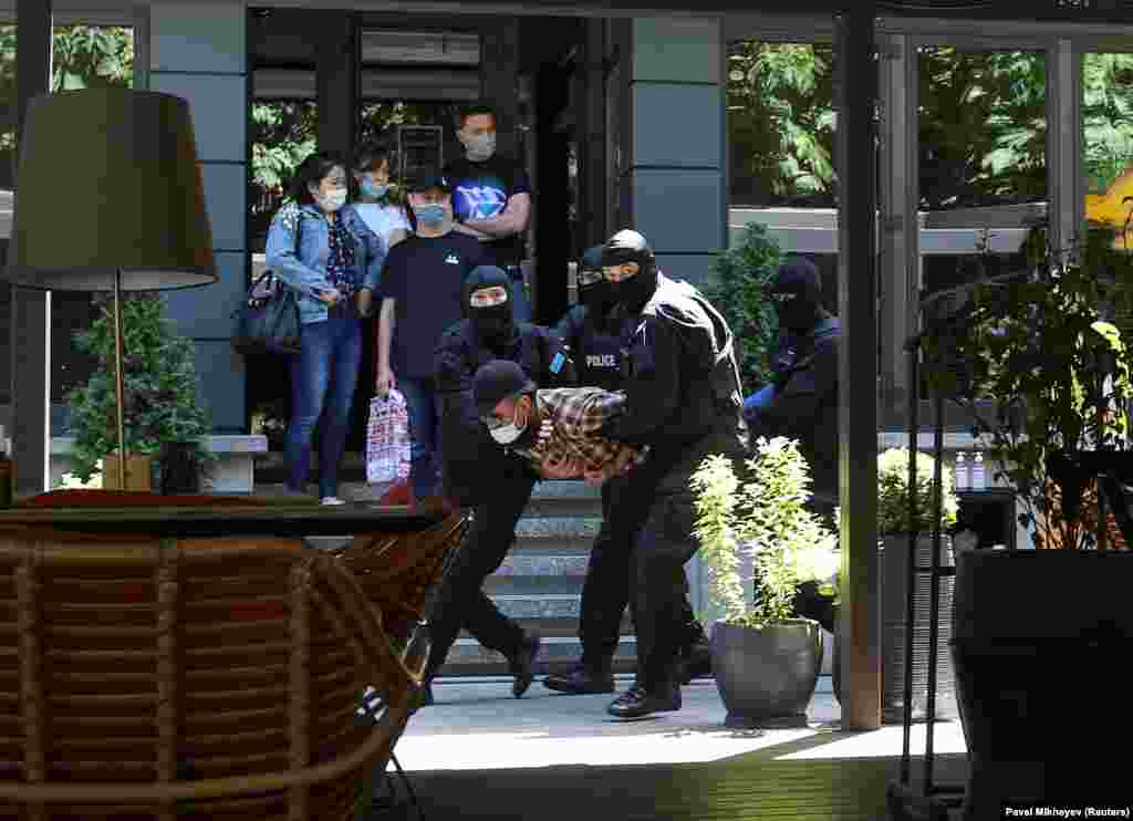 Pedestrians watch police detain a man during an unsanctioned rally held by Kazakh opposition supporters in Almaty.