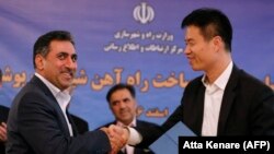 Iranian deputy minister for roads and urban development shakes hands with executive president of China Machinery Industry Construction Group Inc, during a signing ceremony in Tehran, March 7, 2018
