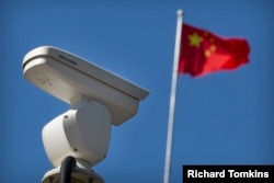 A Hikvision camera mounted near a Chinese national flag.