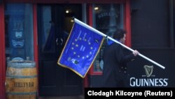 Мужчина с флагом ЕС проходит рядом с пабом в Дублине, столице Ирландии. 4 декабря 2017 года.