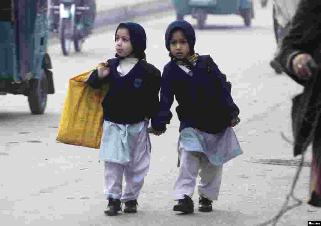 Girls carry their school bags as they walk along a road while heading to their school after it reopened in Peshawar, Pakistan, on January 12.&nbsp;​(Reuters/Khuram Parvez)