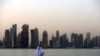 A man looks at his phone on the corniche in the Qatari capital Doha on July 2