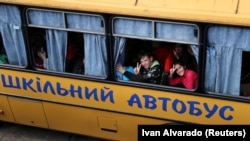 Дети жестикулируют во время эвакуации из оккупированного российскими войсками Купянск на фоне нападения России на Украину, на окраине Харькова, 30 мая 2022 год