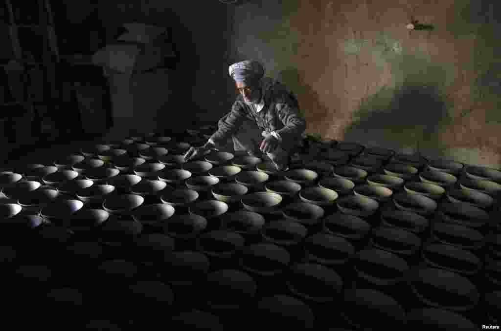 A man arranges bowls made from mud in the outskirts of Kabul, Afghanistan. (Reuters/Omar Sobhani)