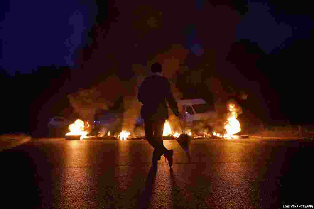 A protester looks at a fire displayed on a traffic circle as trade union members block trucks in Donges, western France, to protest against the government&#39;s new labor law. (AFP/Loic Venance)