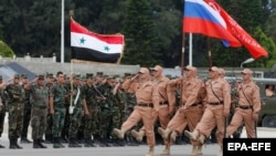 Сирия. 2016-жылдын 4-майында Латакия провинциясындагы Хмеймим аскердик базасында сириялык бөлүк менен биргеликте өткөрүлүүчү Жеңиш күнүнүн парадынын репетициясы учурунда орусиялык жоокерлер марш тээп жатышат.