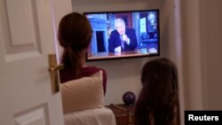 Члени британської родини дивляться виступ прем’єра Бориса Джонсона по телевізору щодо боротьби з коронавірусом. 10 травня 2020 року