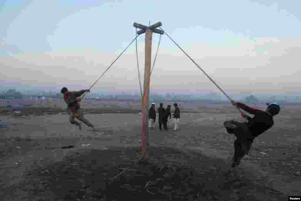 Boys play on a swing on the outskirts of Peshawar, Pakistan. (Reuters/Khuram Parvez)