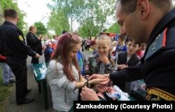 Міліцыянт сьмяецца, зашчоўкваючы кайданкі на руках дзяўчынкі