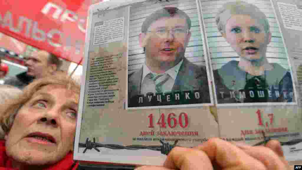 A woman holds a placard with pictures of jailed ex-premier Yulia Tymoshenko and jailed opposition leader Yuriy Lutsenko.