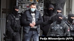 Maskirani policajci privode Veljka Belivuka, poznatog pod nadimkom "Velja Nevolja", sa lisicama na rukama nakon racije na stadionu "Partizan" u Beogradu, 4. februara 2020.