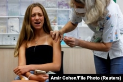 В Израиле, где сделано это фото, как и в Сингапуре, власти перешли к вакцинации подростков — получить прививку теперь могут все, кому исполнилось 12 лет