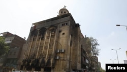 Christians look at a church that was set on fire during clashes between Muslims and Christians in the heavily populated area of Imbaba in Cairo on May 8.