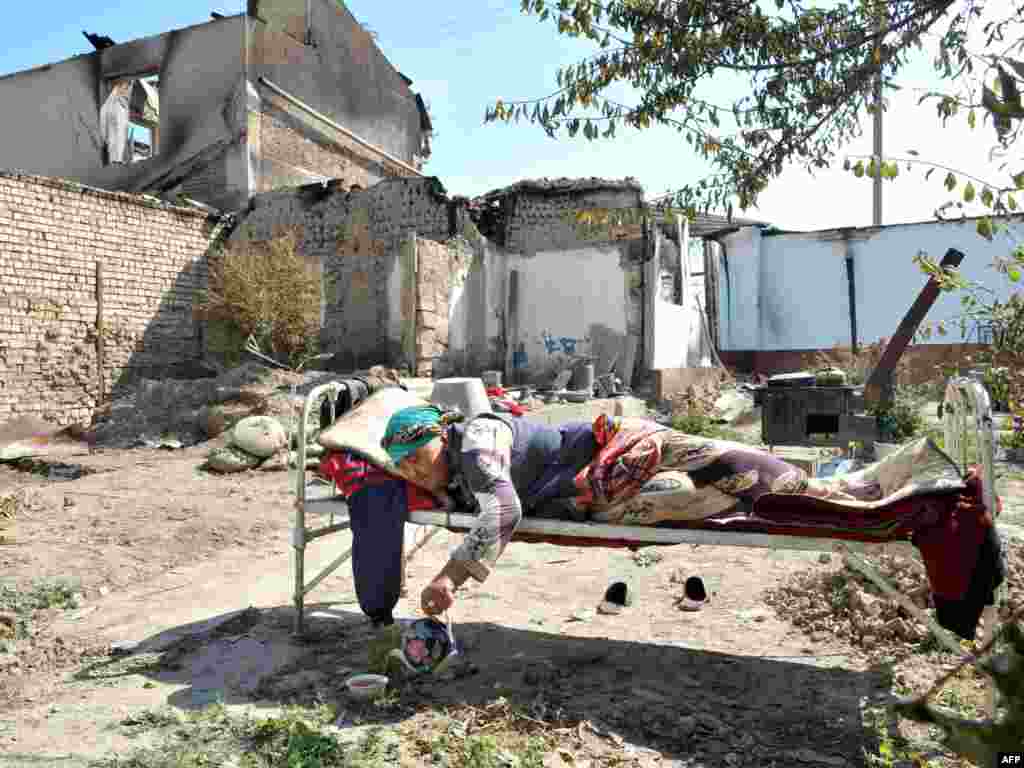 Пожилая узбечка лежит на кровати посреди пепелищ своего сгоревшего дома в Оше. 20 июня 2010 года.