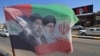 تصاویر روح‌الله خمینی، علی خامنه‌ای و مجتبی خامنه‌ای، رهبران پیشین و فعلی ایران روی پرچم جمهوری اسلامی در شهر کربلا، عراق