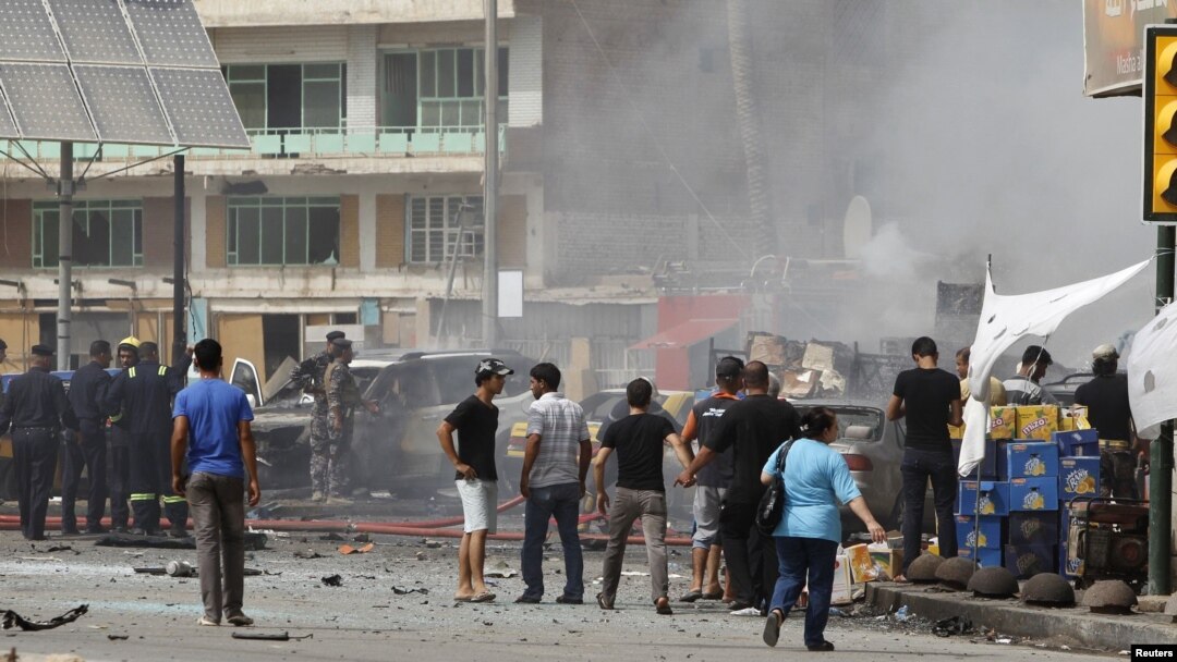 Residents gather at the site of a bomb attack in central Baghdad on July 31 that killed 20 people.