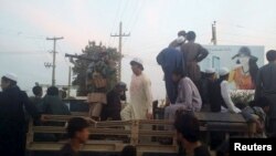 Taliban fighters and residents on top of a military vehicle in Kunduz, a day after the Taliban took control of the city on September 29.