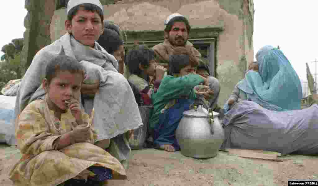 A displaced family waits for a bus. 