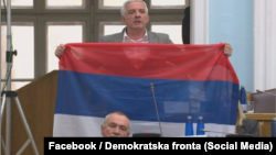 Oopposition Democratic Front deputy Jovan Vucurovic takes out a Serbian tricolor flag during a session of the Montenegrin parliament in Podgorica on March 4.