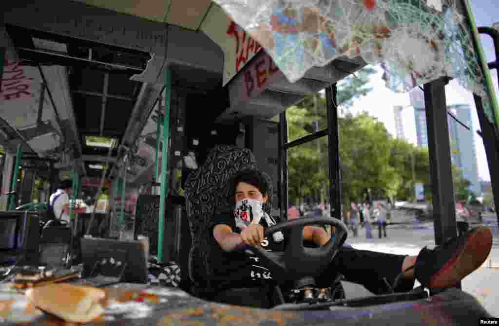 A Besiktas soccer fan uses his team&#39;s scarf as a mask while sitting in a damaged bus on Taksim Square in central Istanbul on June 4.