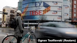 A woman looks up to the EU offices in Skopje that hails "EU For You" in various languages.