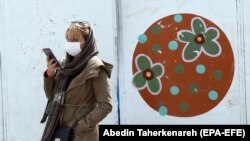 Женщина в маске на улице в Тегеране, 2 марта 2020 года.