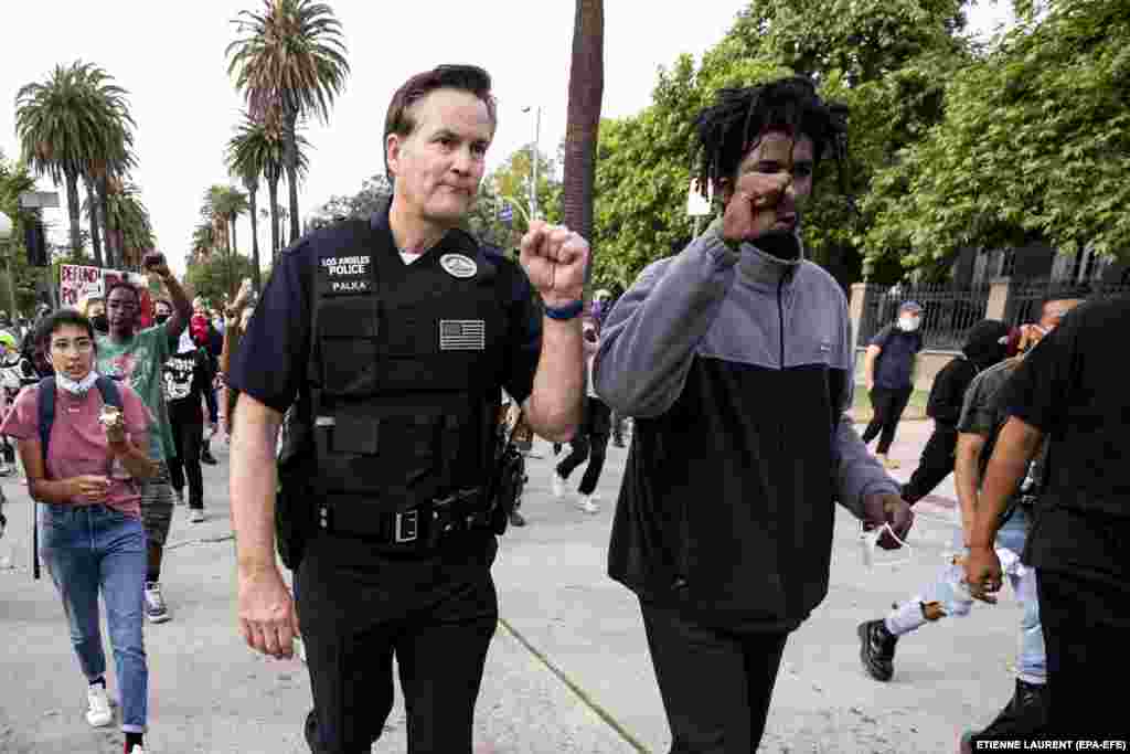 U.S. -- LOS ANGELES GEORGE FLOYD DEATH PROTEST -- epa08461815 LAPD Commander Cory Palka (L) and a protester with whom he negotiated to leave walk away from Los Angeles mayor Eric Garcetti's house as thousands of protesters took the street to demonstrate