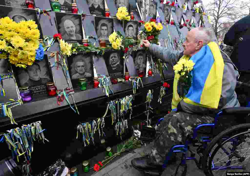 A man in a wheelchair lays flowers at the memorial for Maidan activists who lost their lives during a ceremony marking the fifth anniversary of the start of the Ukrainian Revolution in Kyiv on November 21. (AFP/Genya Savilov)