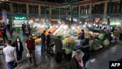 People, some wearing protective face masks, grocers stalls displaying produce at the Tajrish Bazaar in Tehran, March 12, 2020