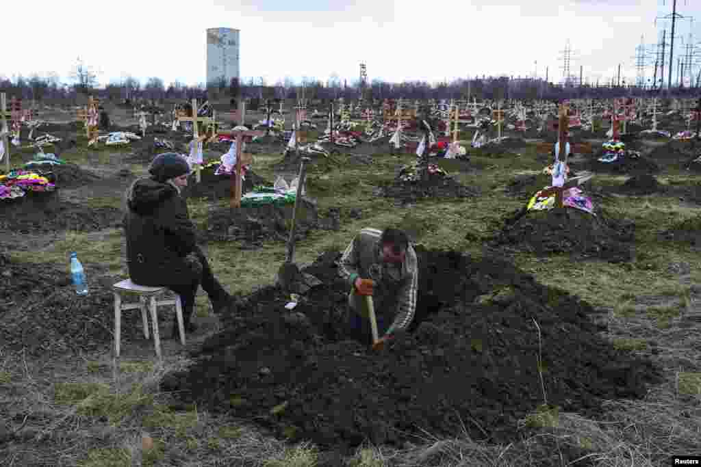 A gravedigger works as his wife watches at a cemetery in Donetsk, Ukraine, where workers killed by a blast at the Zasyadko coal mine will be buried. Thirty-three miners were confirmed dead. Mine officials said the explosion was most likely caused by gas and not fighting in the war between Moscow-backed rebels and Ukraine government forces. (Reuters/Marko Djurica)