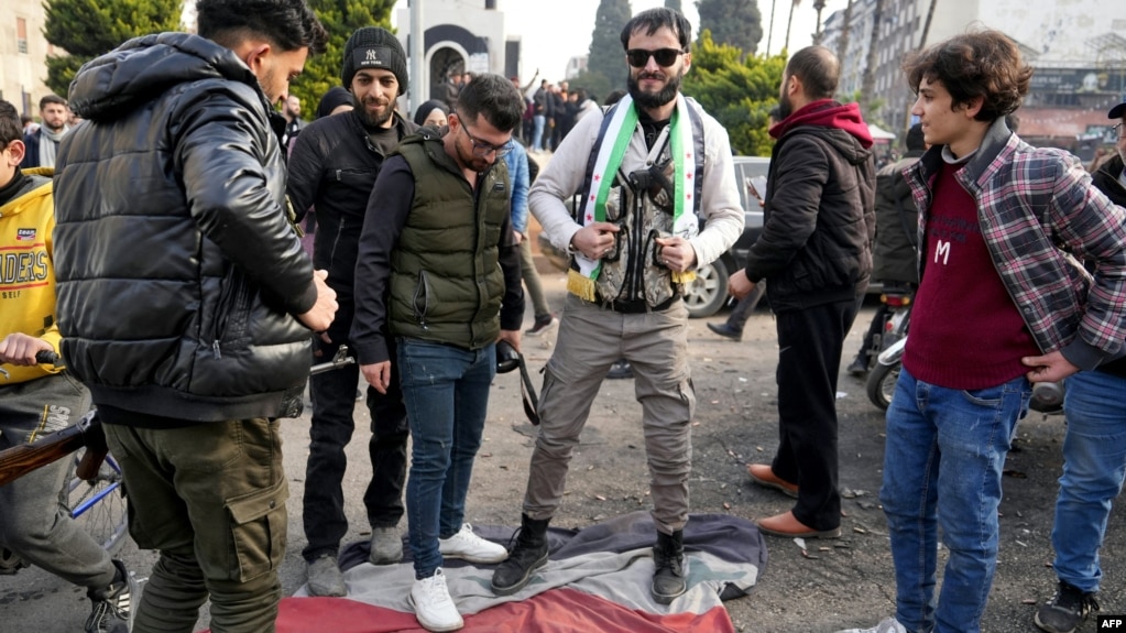 Syrians step on a regime flag as they celebrate near the Clock Tower in the central city of Homs on December 8.