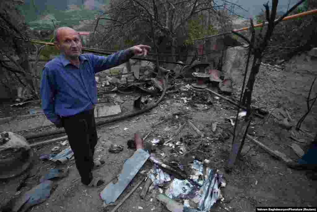 Човек стои во близина на урнатините на куќата, за која локалното население тврди дека е оштетена од гранатирањето на азербејџанските сили во градот Хадрут во спорниот регион Нагорно Карабах.