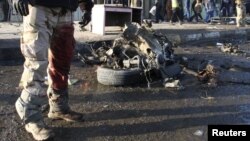 A wounded soldier stands near the remains of a vehicle used in a bomb attack in Sadr city in northeastern Baghdad on January 24.