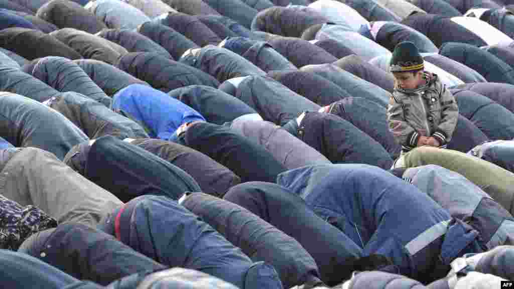 A little boy looks at the adult Muslims traditionally praying outside at one of the central squares in Bishkek. (AFP/Vyacheslav Oseledko)