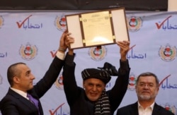 Ашраф Ғани (ортада) Ауғанстан президенті болып тағы бір мерзімге сайланғаны туралы ресми шарада тапсырылған сертификатты көрсетіп тұр. Кабул, 19 ақпан 2020 жыл.