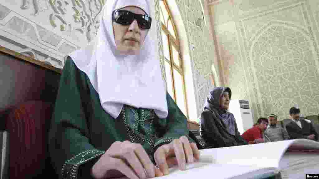 A Tajik woman reads the Koran in Braille at the Islamic Center in Dushanbe. (Reuters/Nozim Kalandarov)
