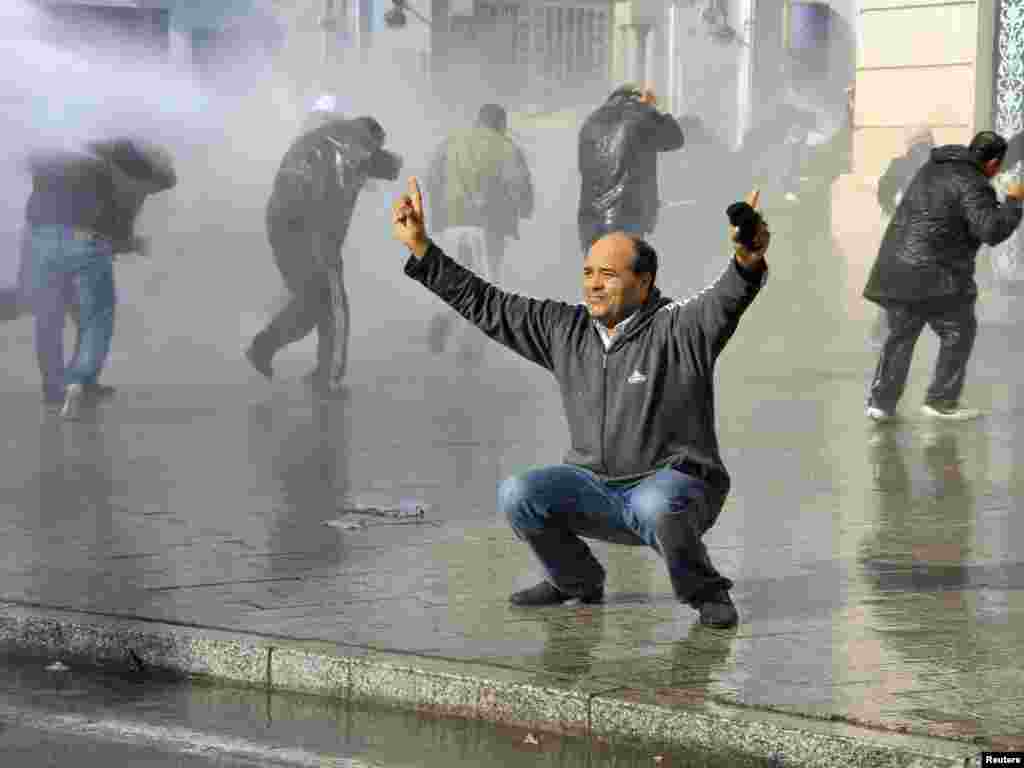 A demonstrator reacts as security forces use water cannon to disperse protesters in downtown Tunis on January 17. Tunisian security forces used water cannon, tear gas, and fired shots in the air as demonstrators took to the streets &nbsp;demanding that the ruling party of the ousted president give up power&nbsp;. Photo by Reuters