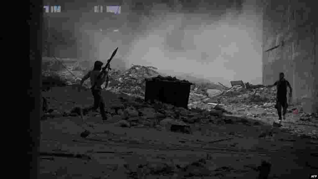 A Syrian rebel fighter carrying a rocket-propelled grenade moves across open ground under heavy tank fire from Syrian government forces during an intense battle in the al-Arqub neighborhood of Aleppo on September 26. (AFP/Zac Baillie) 