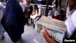 پول افغانی در دست یک صراف سیار در شهر کابل. عکس از آرشیف