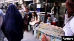 A person holds a bundle of Afghan banknotes at a money exchange market, following banks and markets reopening in Kabul on September 4.